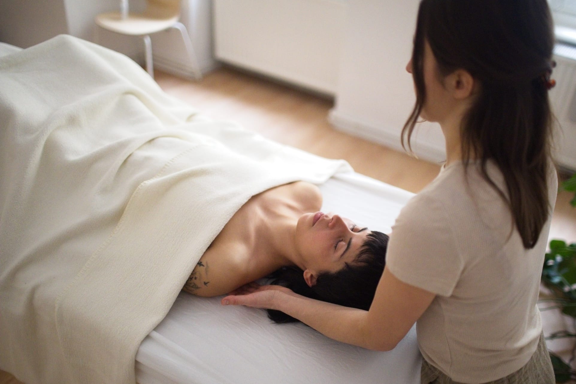 Hands-on somatic bodywork session in Berlin-Kreuzberg: the practitioner supports the head and neck while the client rests